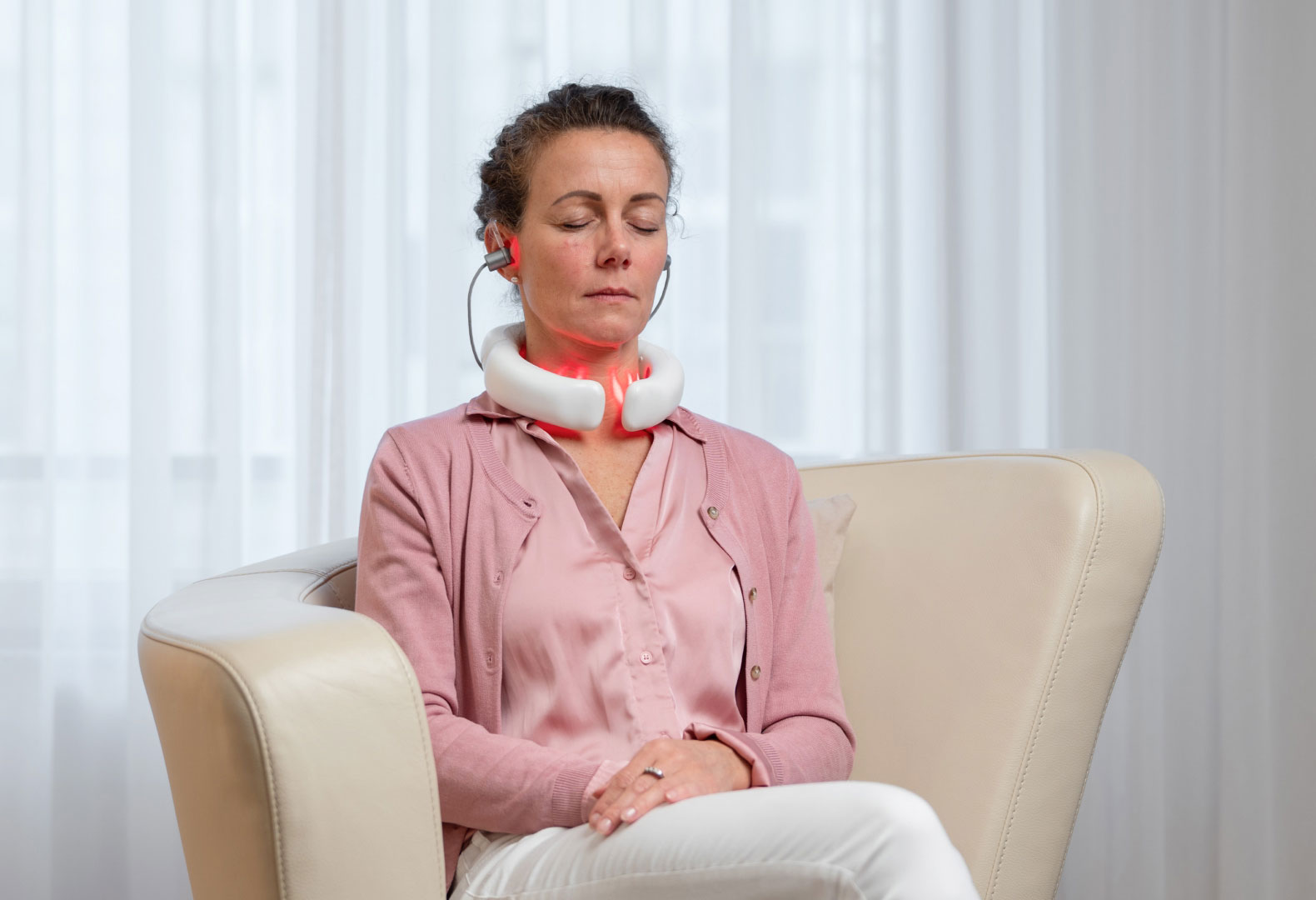 LumoHome - Energie für deine Zellen. Frau nutzt das LumoHome Lasertherapiegerät entspannt im Sitzen