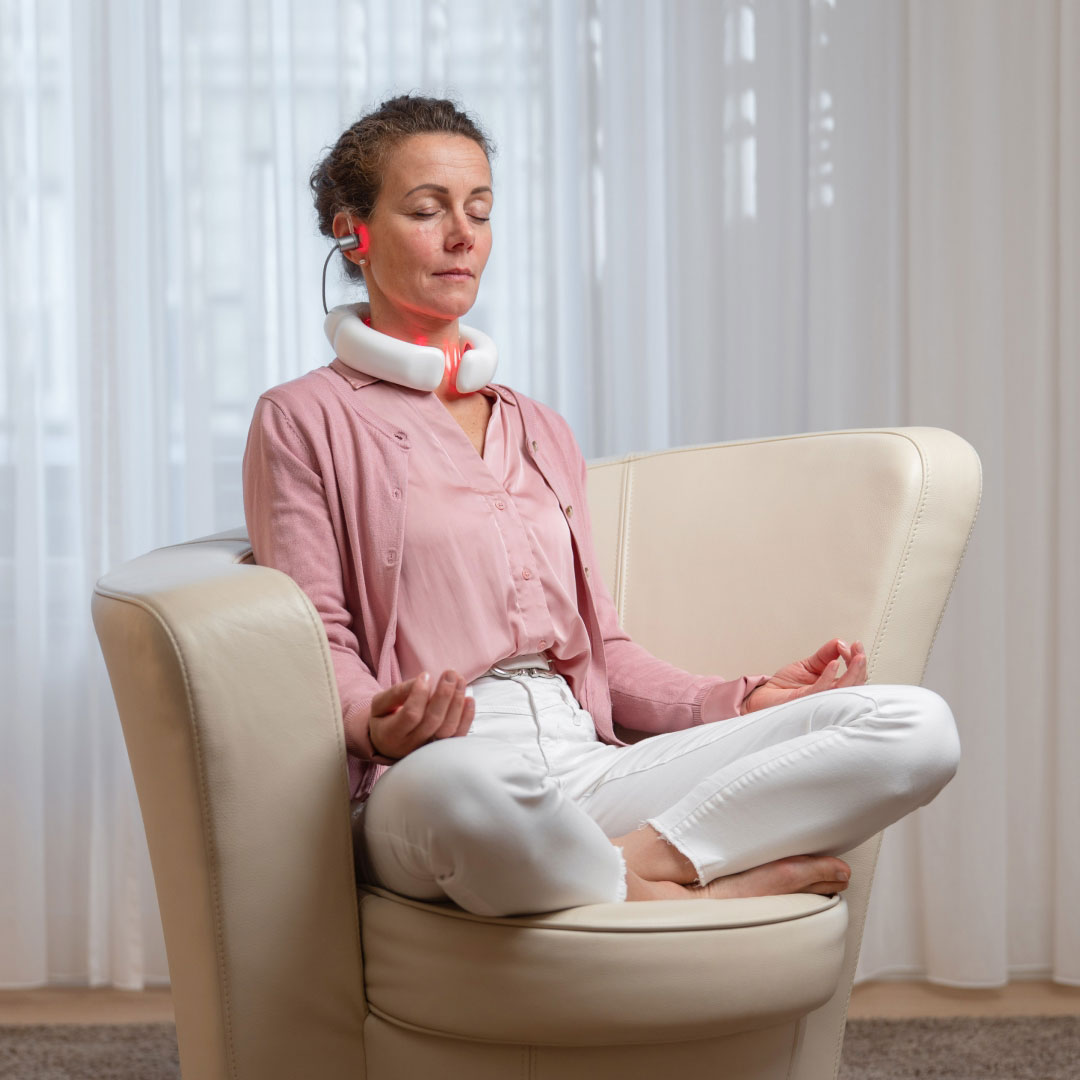 LumoHome Lasertherapie Frau sitzt entspannt im Wohnzimmer und nutzt den LumoHome Laser zur sanften Anwendung am Innenohr.“